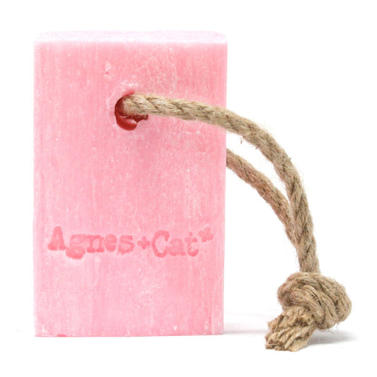 Artisanal pink soap bar with a natural hanging rope, featuring delicate floral textures and a fresh aesthetic.