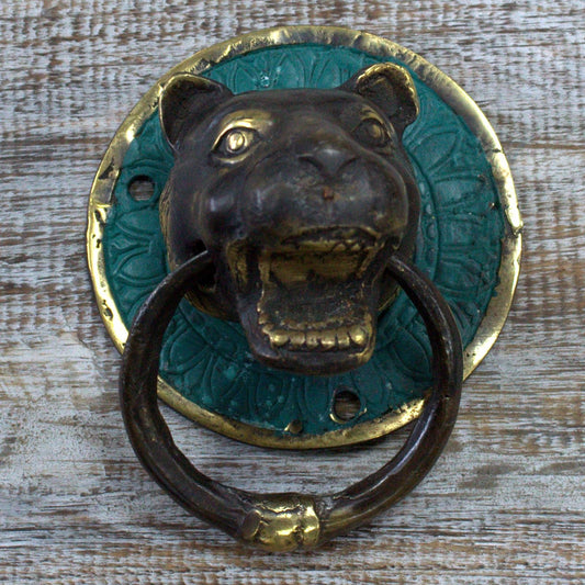 Detailed ornate brass door knocker shaped like a tiger's head with a classic ring in its mouth.