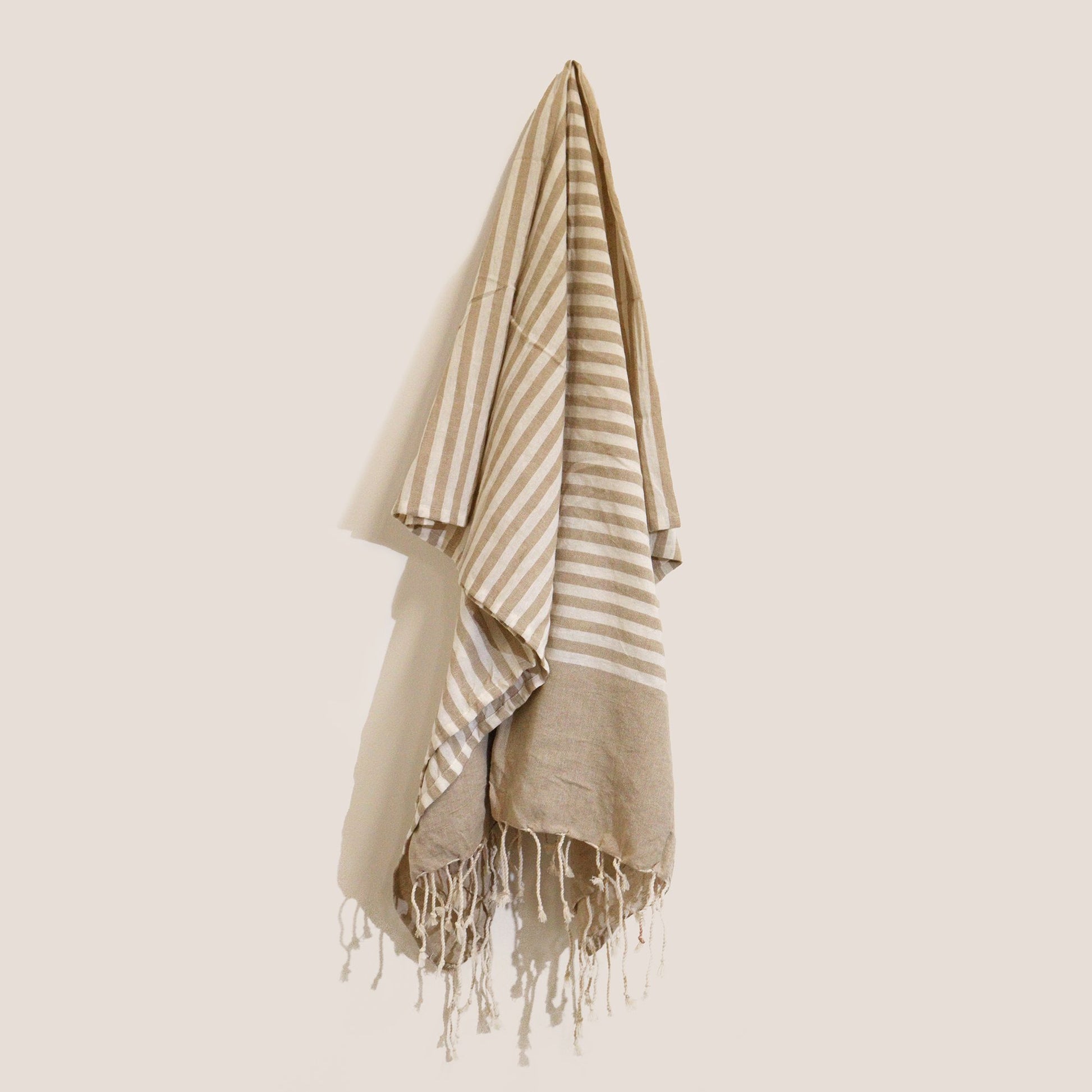 Handcrafted cotton pario throw in a neutral warm sand colour with a textured weave and fringed edges.