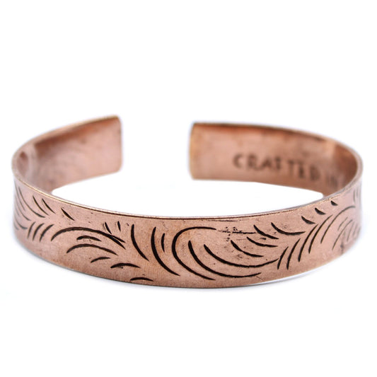 Wide copper Tibetan cuff bracelet featuring intricate embossed tribal swirl patterns and an adjustable open-back design.