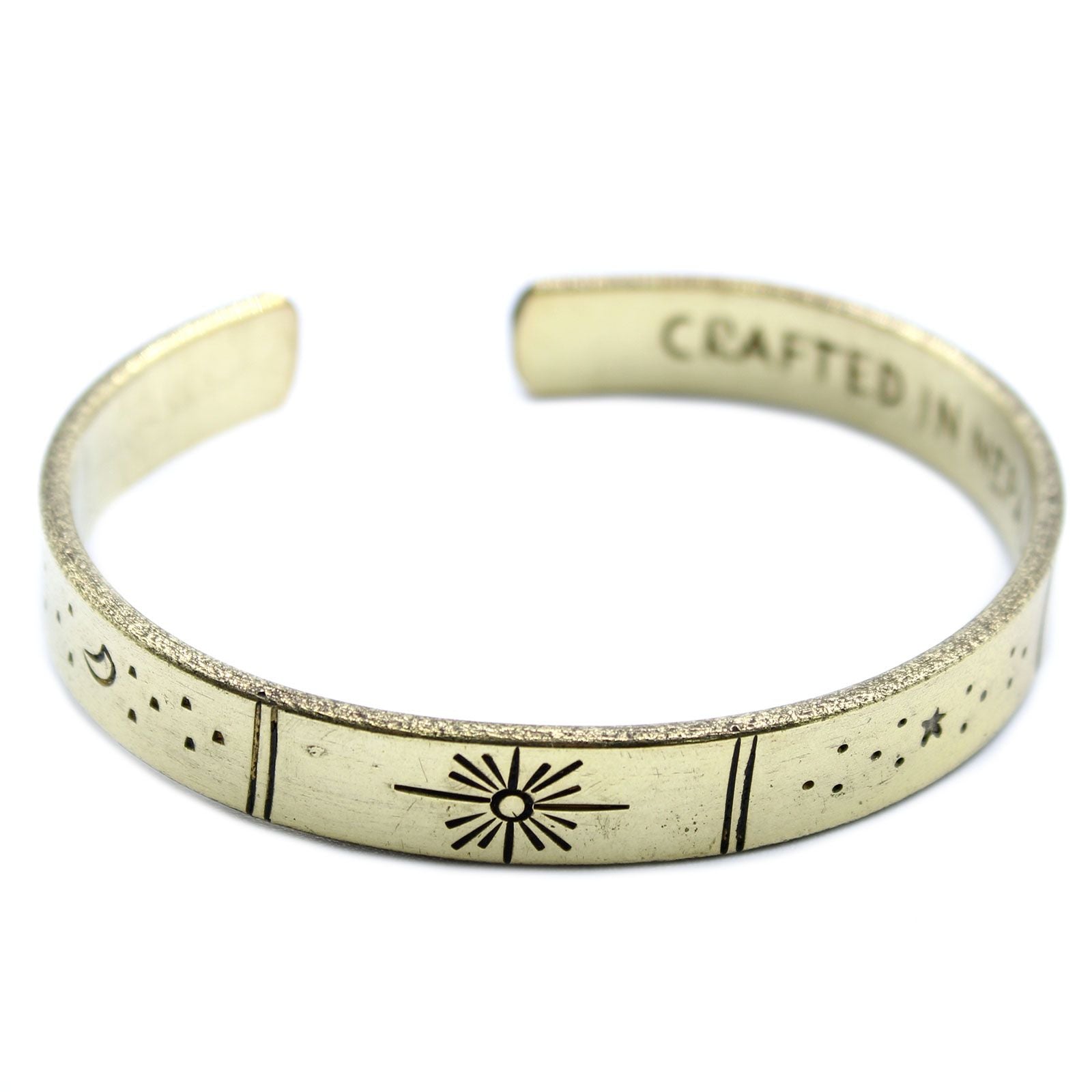 Handcrafted adjustable brass bracelet featuring etched celestial designs of stars, the sun, and the earth.
