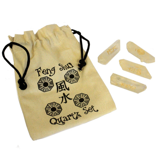 Four polished clear natural quartz crystals engraved with golden Feng Shui symbols on a dark surface.