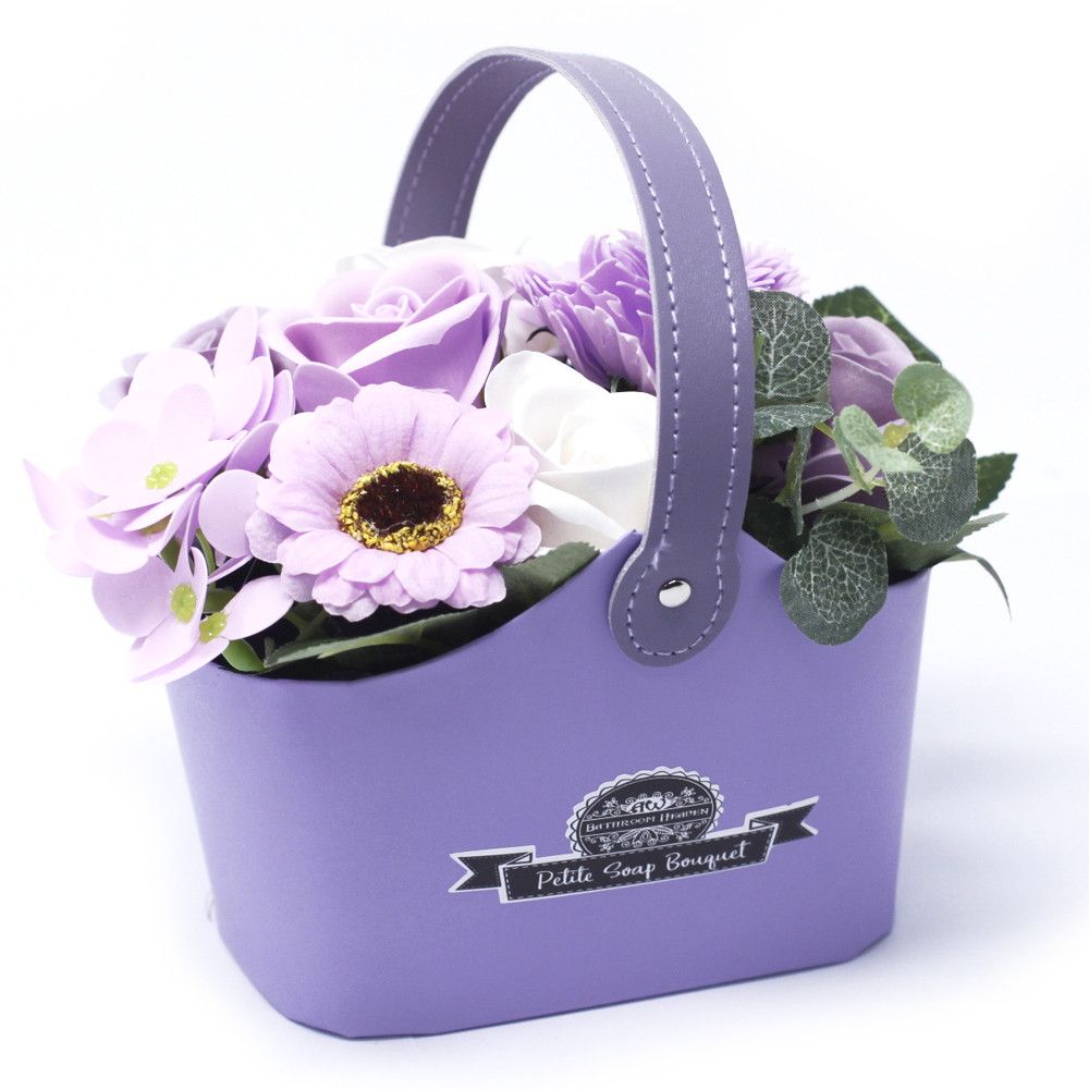Artistically arranged bouquet of realistic purple soap roses in a small wicker petite basket.
