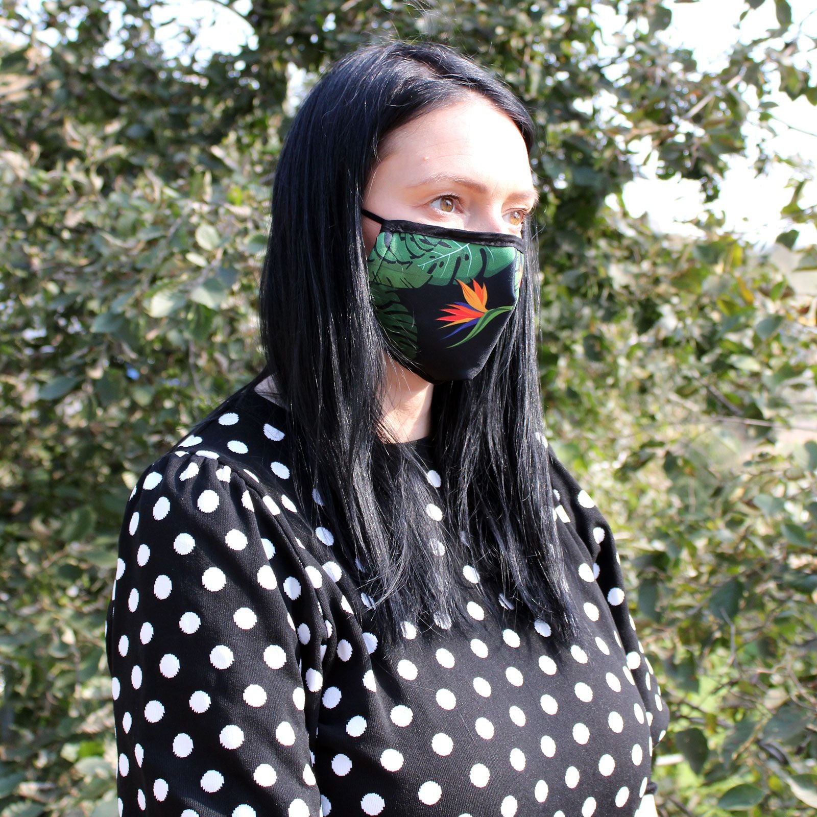 Adult reusable fabric face covering featuring a vibrant green jungle leaf pattern on a white background.