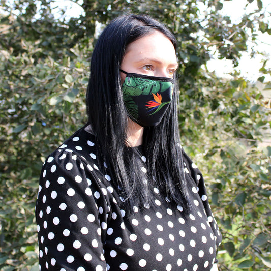 Adult reusable fabric face covering featuring a vibrant green jungle leaf pattern on a white background.