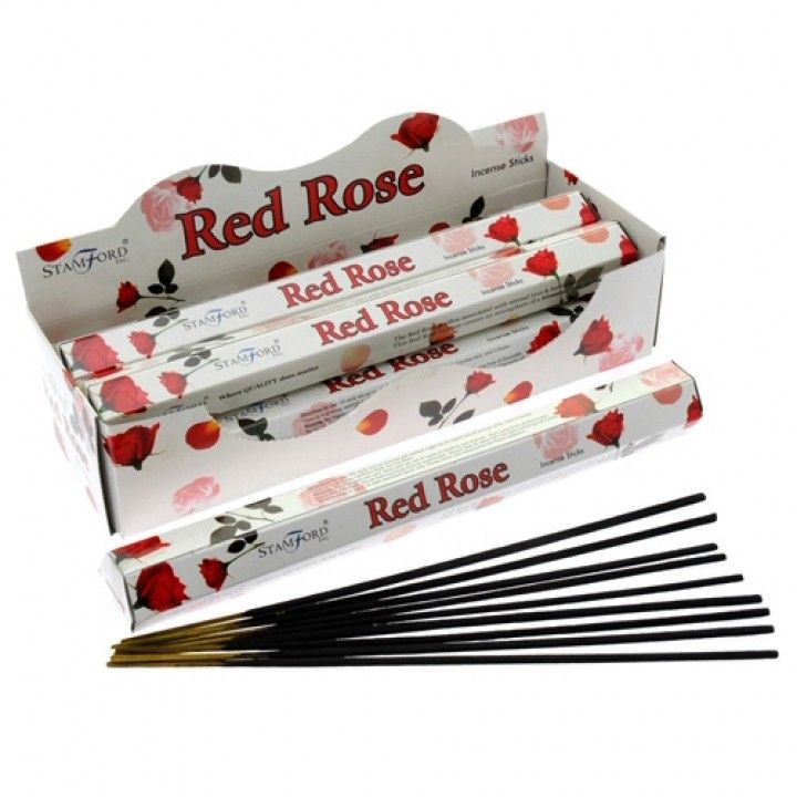 Hexagonal box and several hand-rolled red rose scented incense sticks on a neutral surface.
