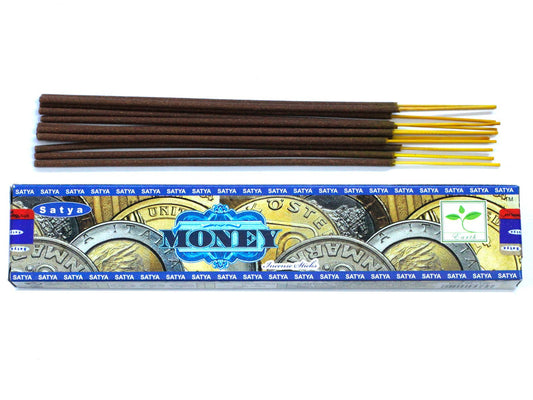 Hand-rolled incense sticks in a yellow box labeled Money, resting on a wooden surface with aromatic smoke rising.