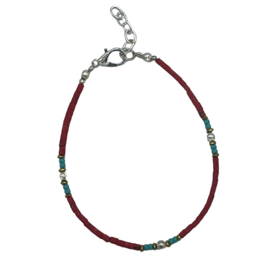 Handcrafted Nepalese bracelet featuring vibrant red coral beads and intricate silver-toned tribal accents.