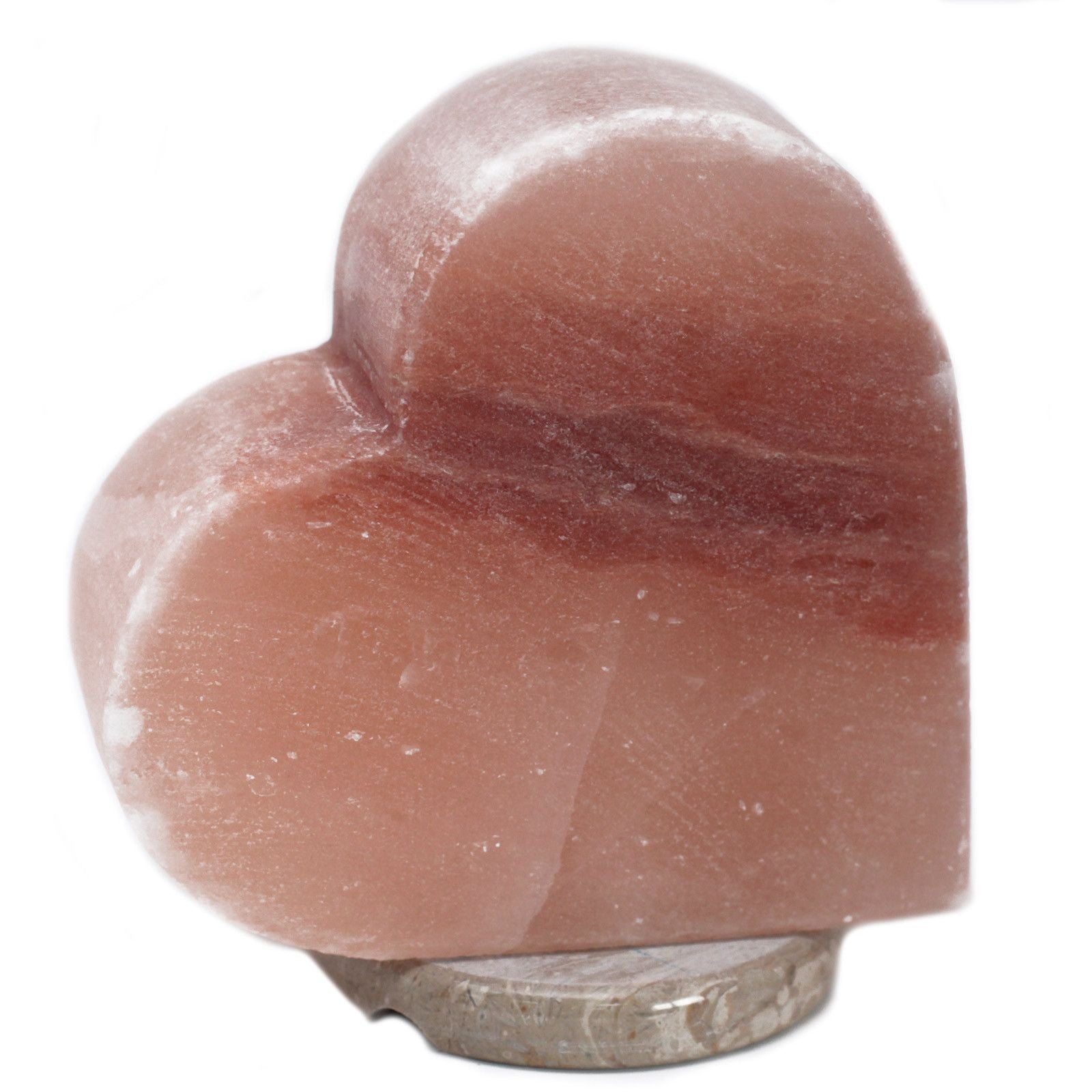 Hand-carved heart-shaped pink Himalayan salt lamp glowing with a warm orange light on a wooden base.