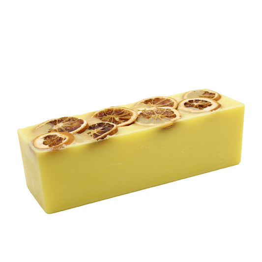 Hand-crafted orange soap loaf topped with dried orange slices on a rustic wooden surface.