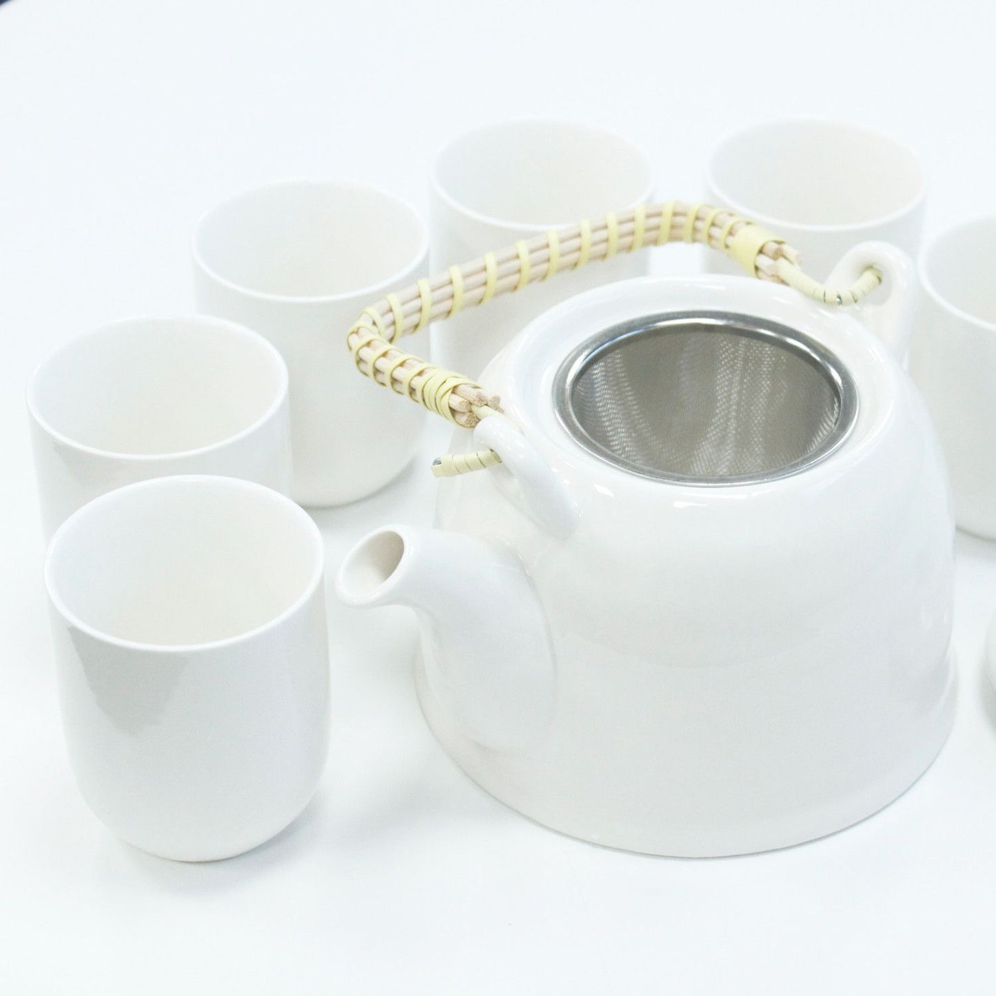 Elegant classic white ceramic teapot with a metal strainer lid and six matching small tea cups in a gift box.