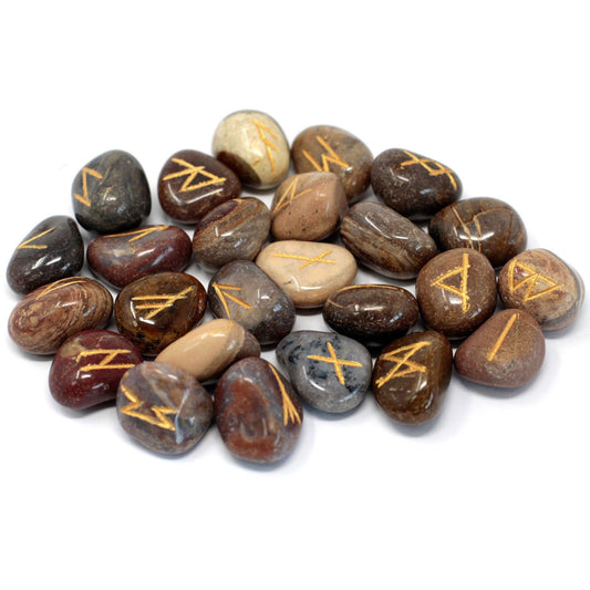 Tumbled fancy jasper stones engraved with traditional rune symbols laid out next to a small drawstring pouch.