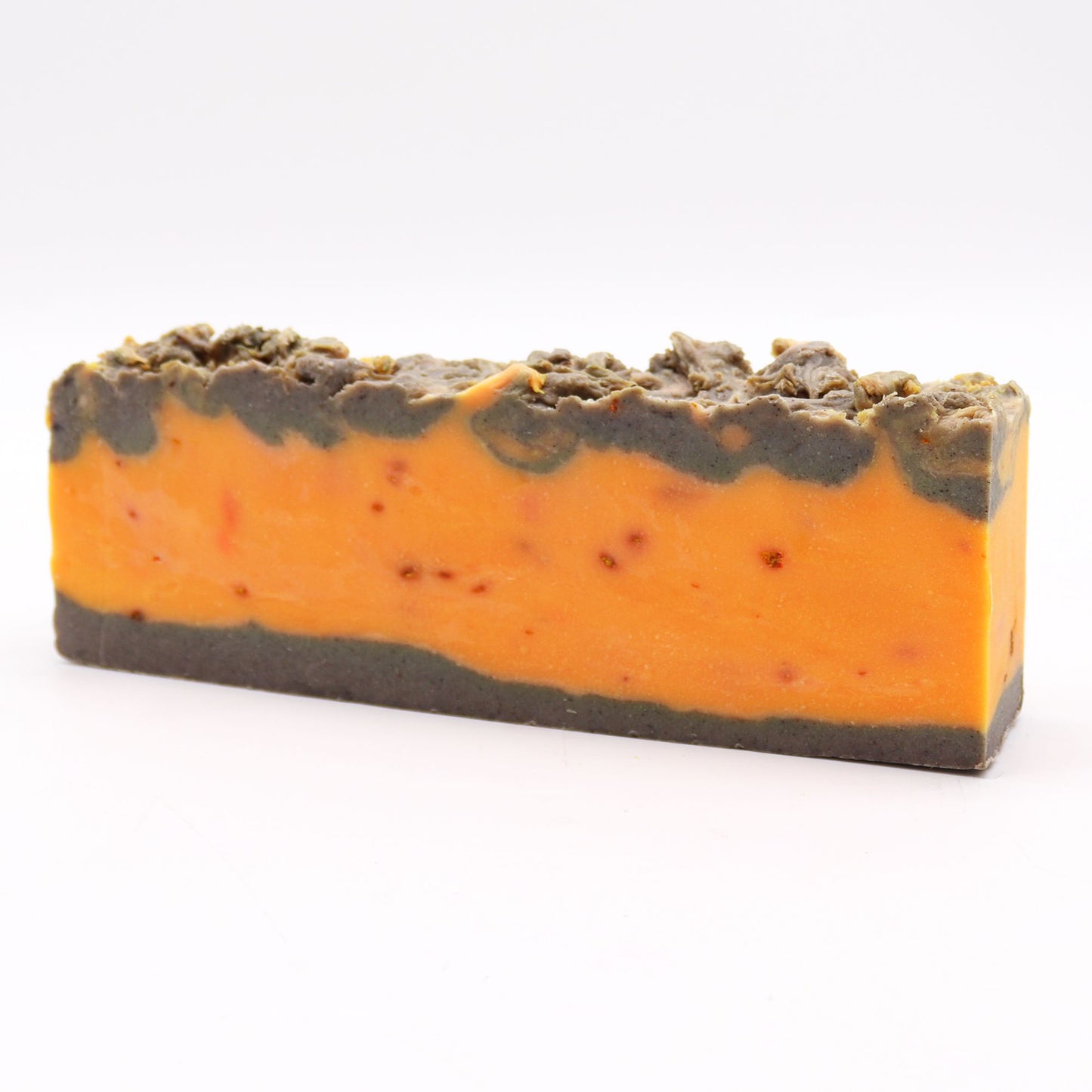 Handmade olive oil soap loaf with visible ground cinnamon and a rustic, textured orange and brown appearance.