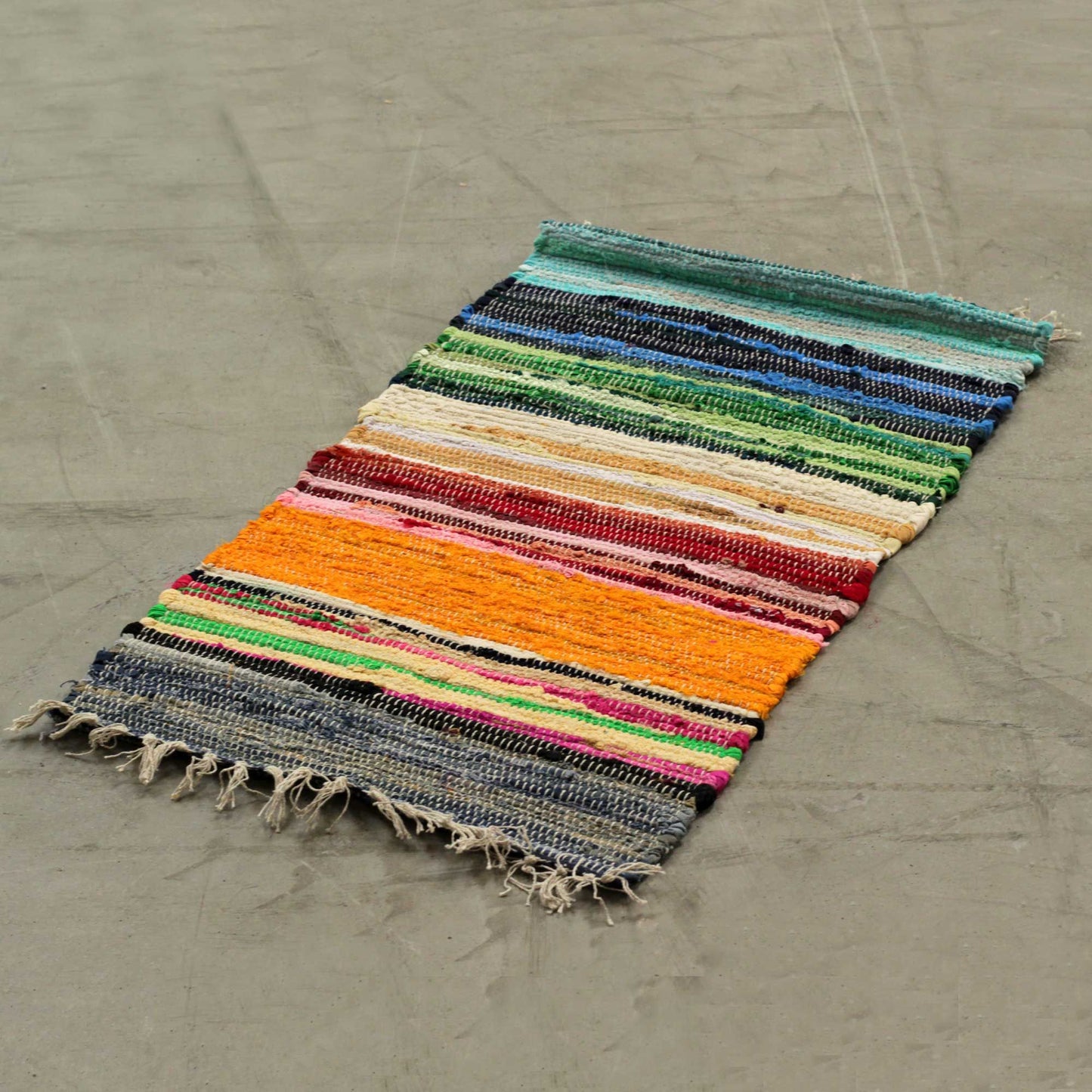 Handwoven small rag rug featuring vibrant rainbow stripes and a textured premium finish.
