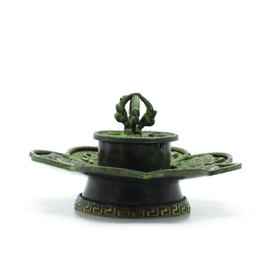 Handcrafted flower-shaped brass incense holder with a green verdigris finish and embossed Tibetan eight symbols.