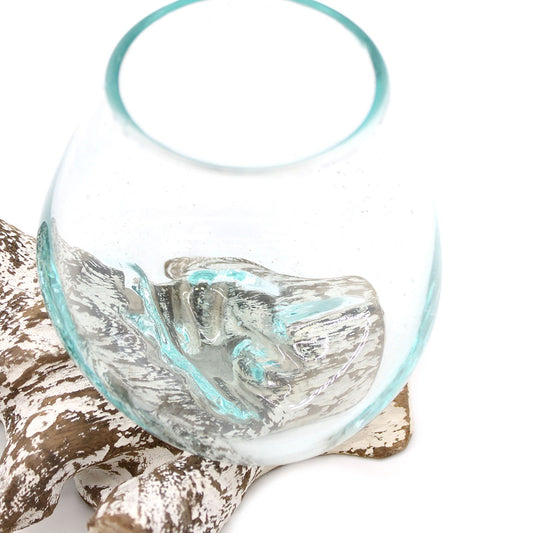 A small hand-blown molten glass bowl artistically slumped over a natural whitewashed wood base.