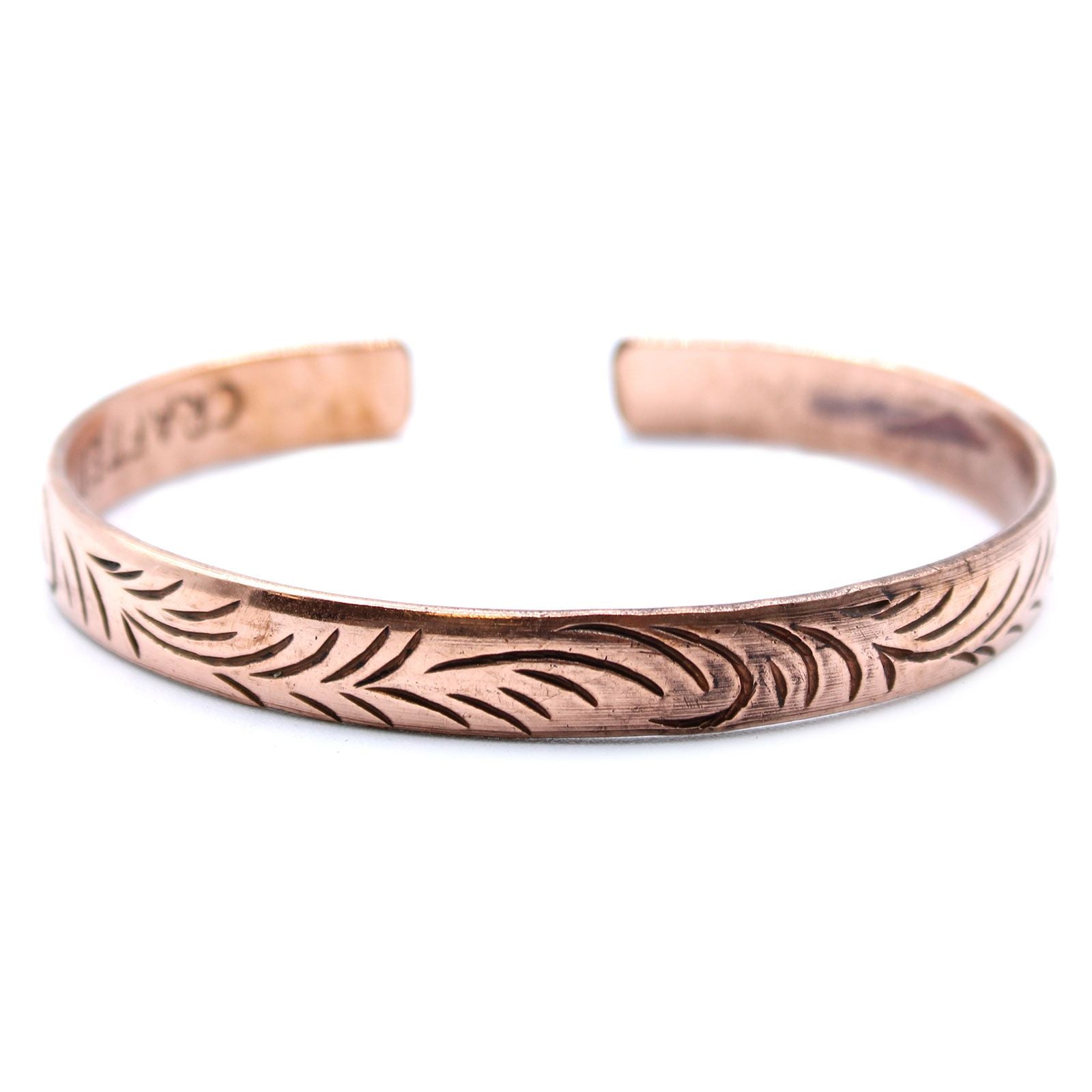 Slim copper cuff bracelet featuring intricate etched tribal swirl patterns on a polished metallic surface.