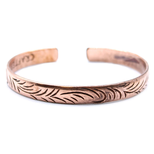 Slim copper cuff bracelet featuring intricate etched tribal swirl patterns on a polished metallic surface.