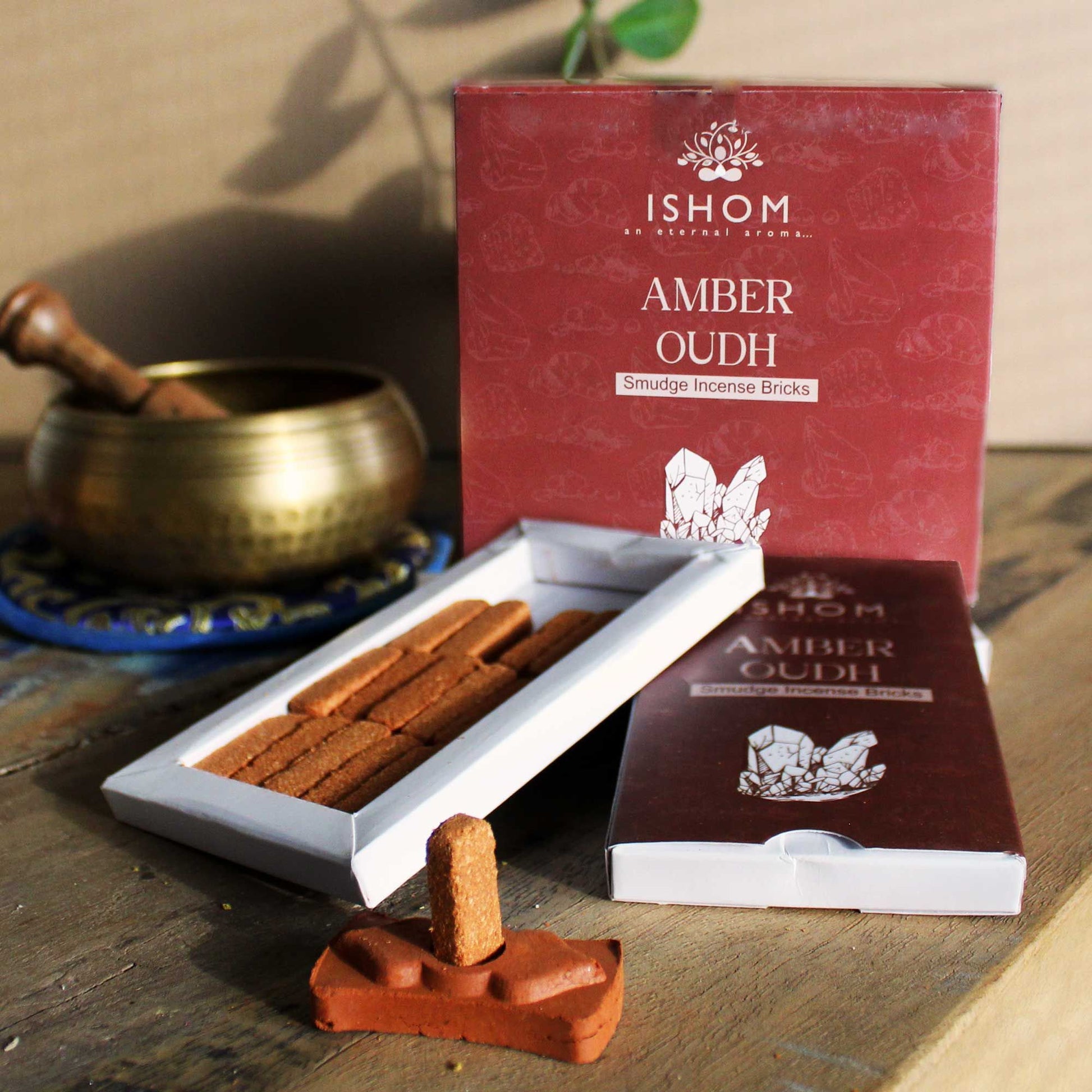 Natural amber wood incense bricks arranged next to a traditional decorative terracotta burner on a plain background.