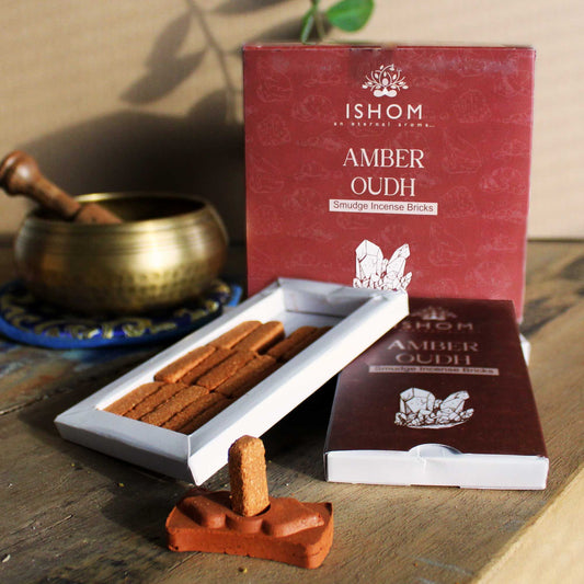 Natural amber wood incense bricks arranged next to a traditional decorative terracotta burner on a plain background.