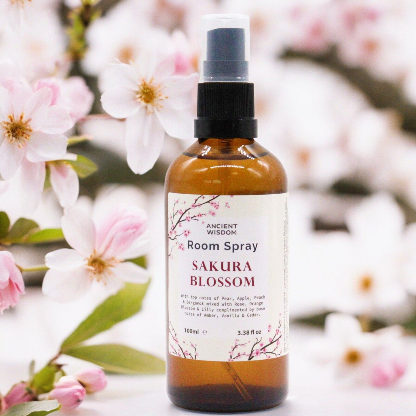 Clear bottle of pink sakura essence room spray with a fine mist spray nozzle on a simple background.