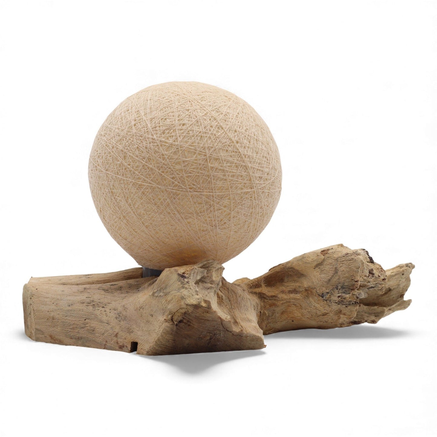 Cream cotton-wrapped sphere lamp on an organically shaped natural driftwood base, emitting a warm glow.