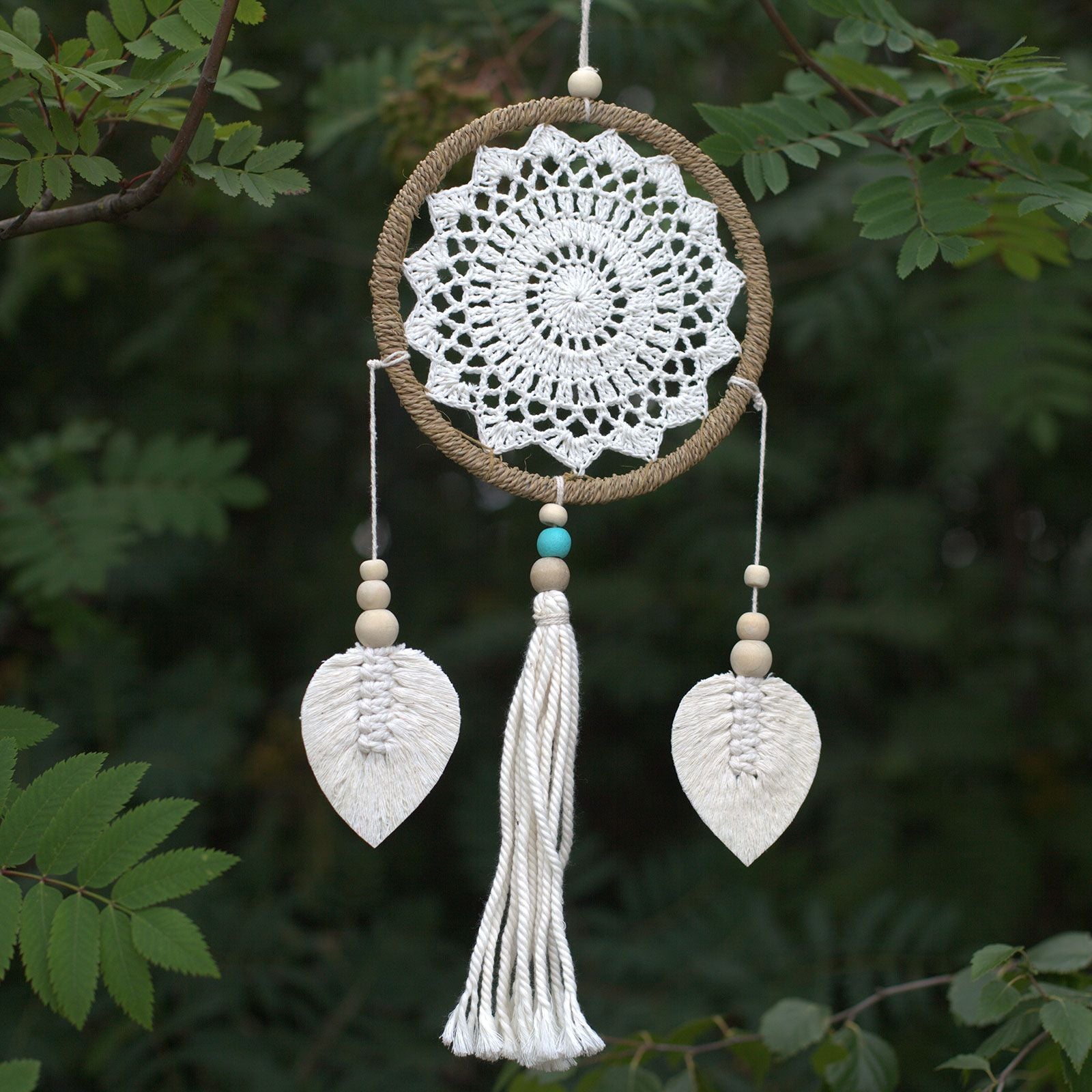Handmade vegan dream catcher made from natural materials with a complex web design and hanging wooden elements.