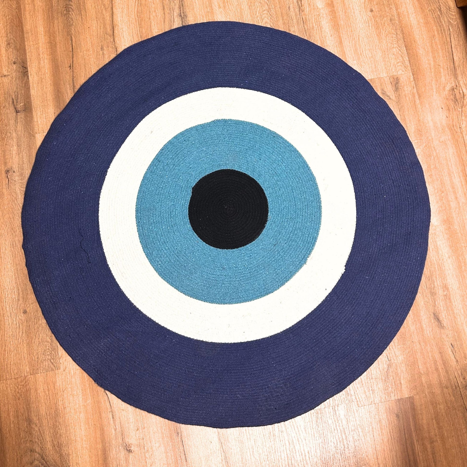 Large round woven cotton rope rug featuring a bold blue and white evil eye motif.