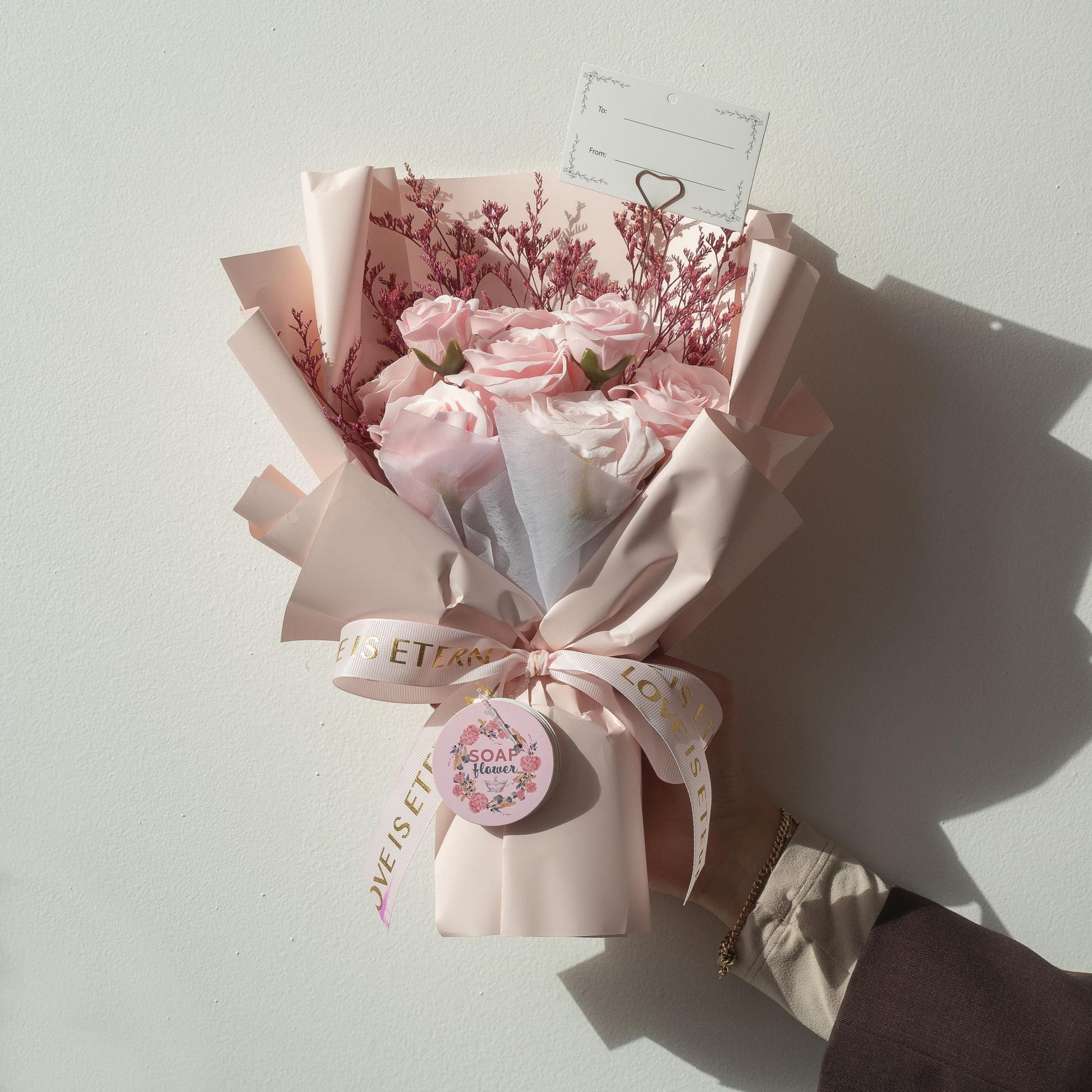Large bouquet of realistic pink soap roses wrapped in pale pink paper with a satin ribbon.
