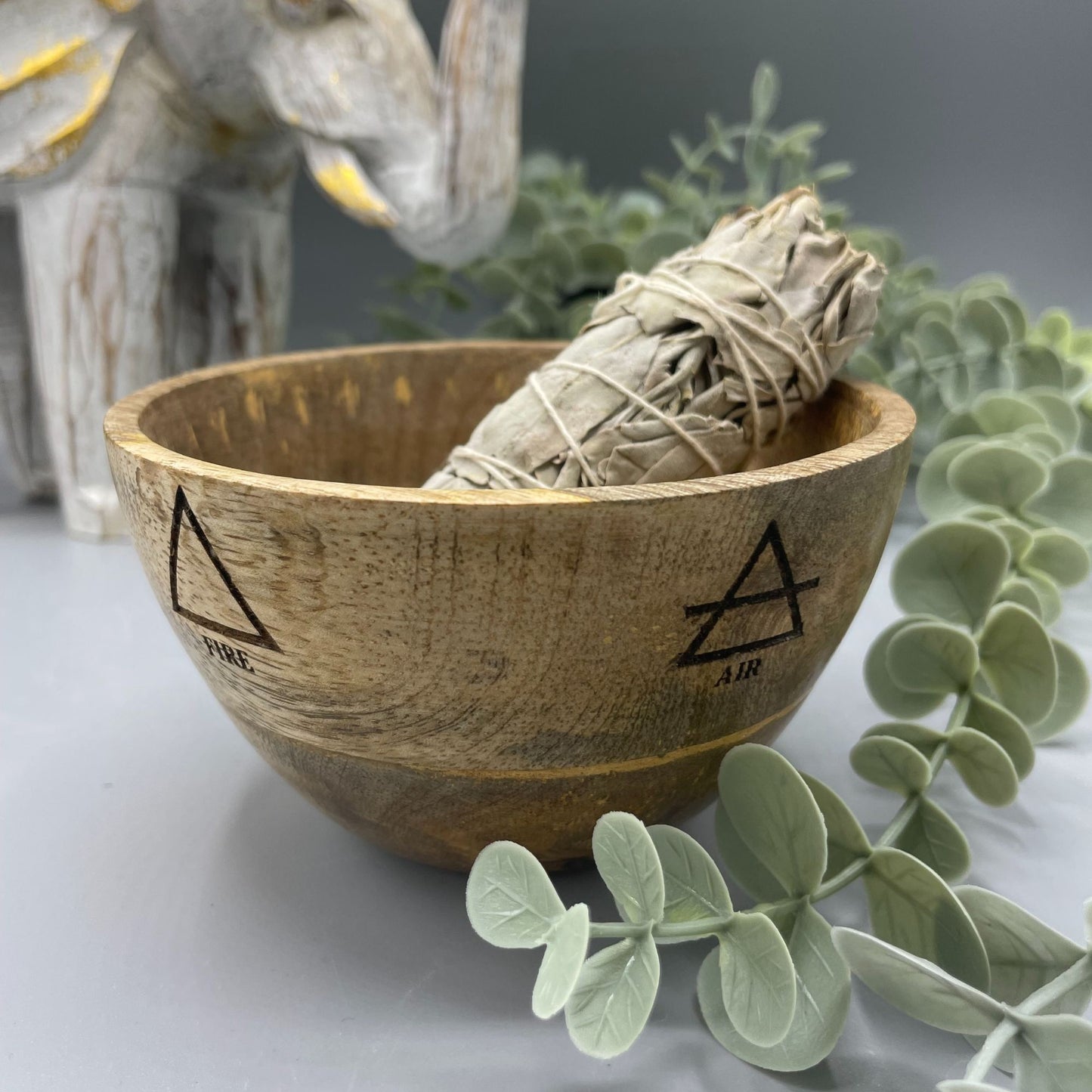 Round wooden ritual bowl featuring engraved Four Elements symbols in a natural grain finish.