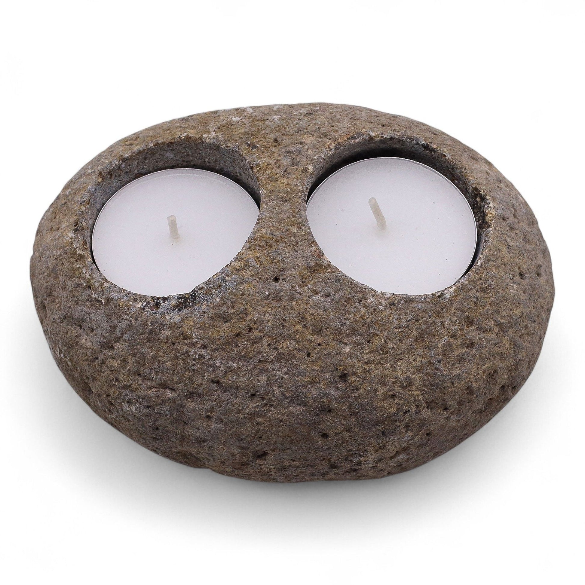 Hand-carved natural grey riverstone candle holder with two circular cutouts for tealight candles on a rustic surface.