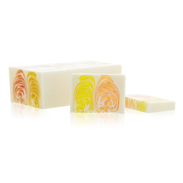 Handcrafted orange and ginger soap loaf with a textured surface and vibrant citrus colours.
