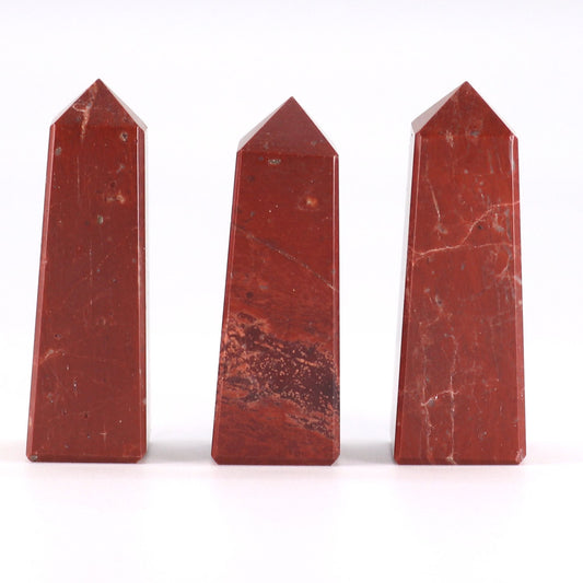Small polished red jasper gemstone obelisk point with a sharp tip and deep brick-red marbled patterns.
