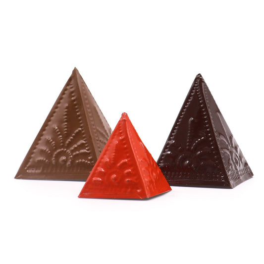 Three wooden pyramid-shaped incense powder moulds in light brown, dark brown, and orange tones.