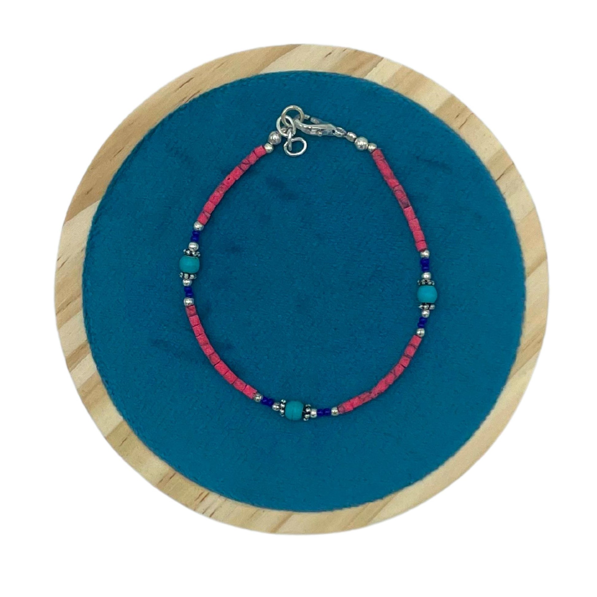 Handcrafted Nepalese bracelet featuring vibrant pink coral and cool turquoise gemstone beads in a striking contrast.