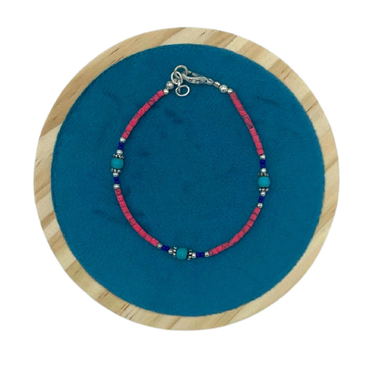 Handcrafted Nepalese bracelet featuring vibrant pink coral and cool turquoise gemstone beads in a striking contrast.