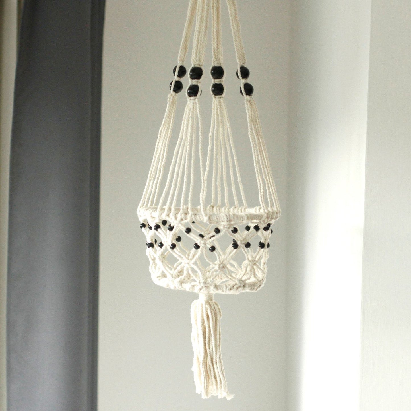 Large cream cotton macrame plant hanger featuring decorative wooden beads and intricate knotted patterns.