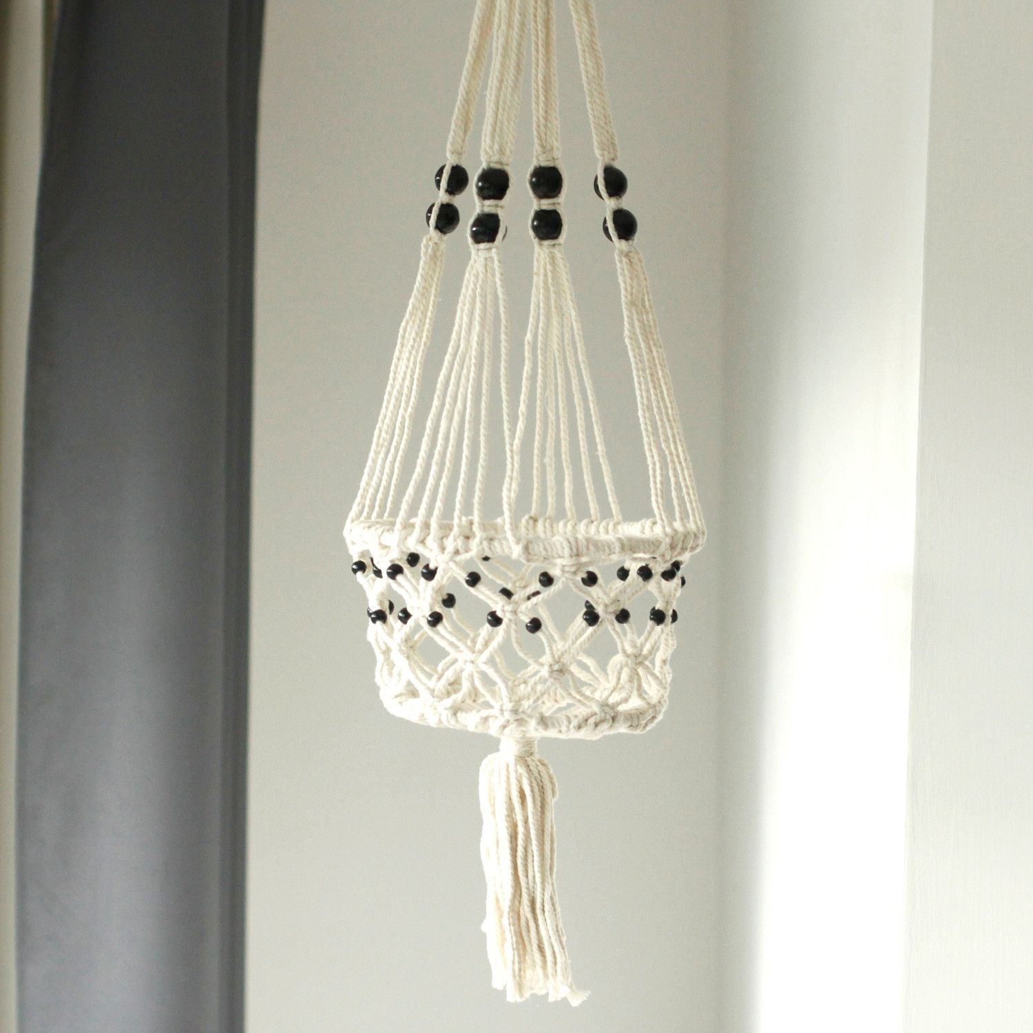 Large cream cotton macrame plant hanger featuring decorative wooden beads and intricate knotted patterns.