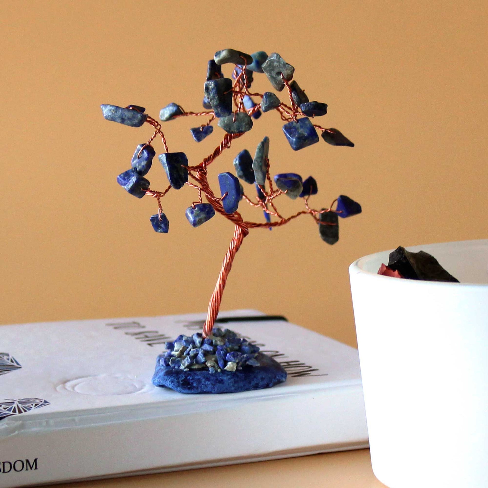 Handcrafted gemstone tree with blue sodalite leaves and wire branches set on a polished blue agate slice base.