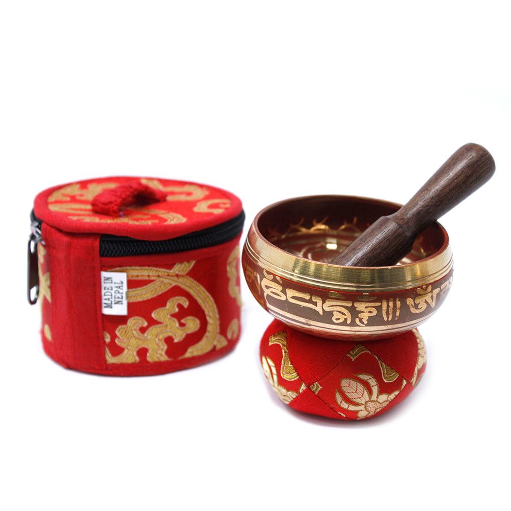 A small vibrant red singing bowl set with a decorative cushion and a wooden striker in a gift box.