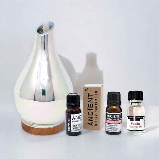 Elegant white ultrasonic aroma diffuser set with essential oils in a minimalist home setting.