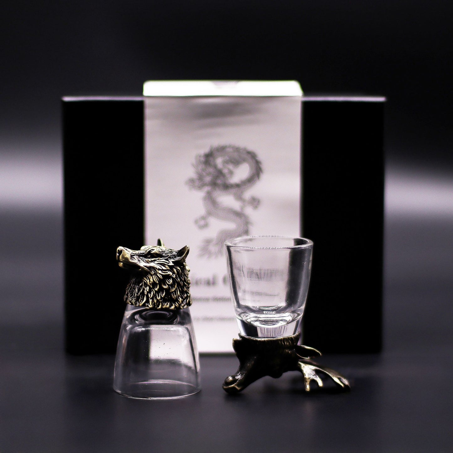 Six antique bronze shot glasses featuring detailed animal head bases including a stag, owl, and wolf on a dark surface.