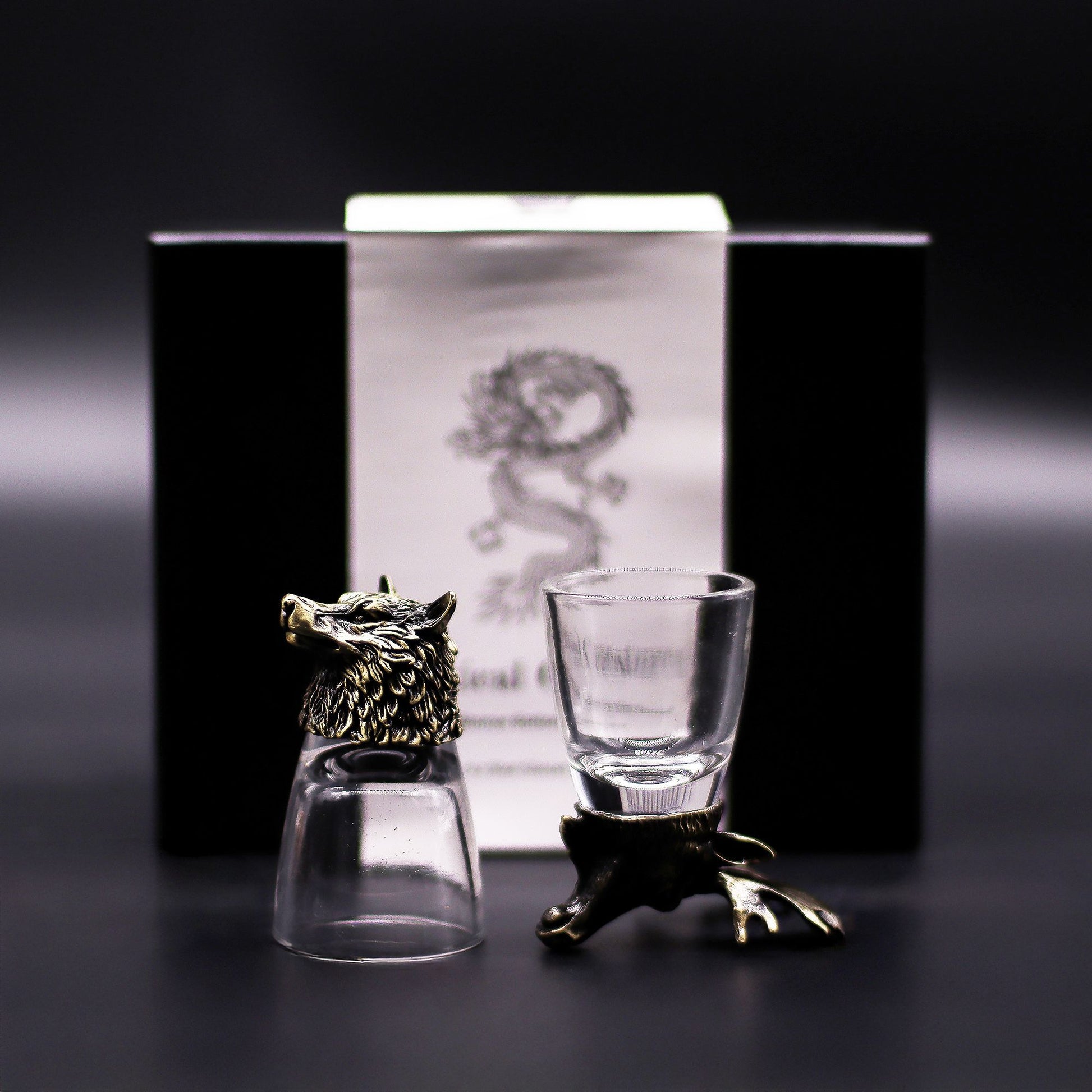 Six antique bronze shot glasses featuring detailed animal head bases including a stag, owl, and wolf on a dark surface.