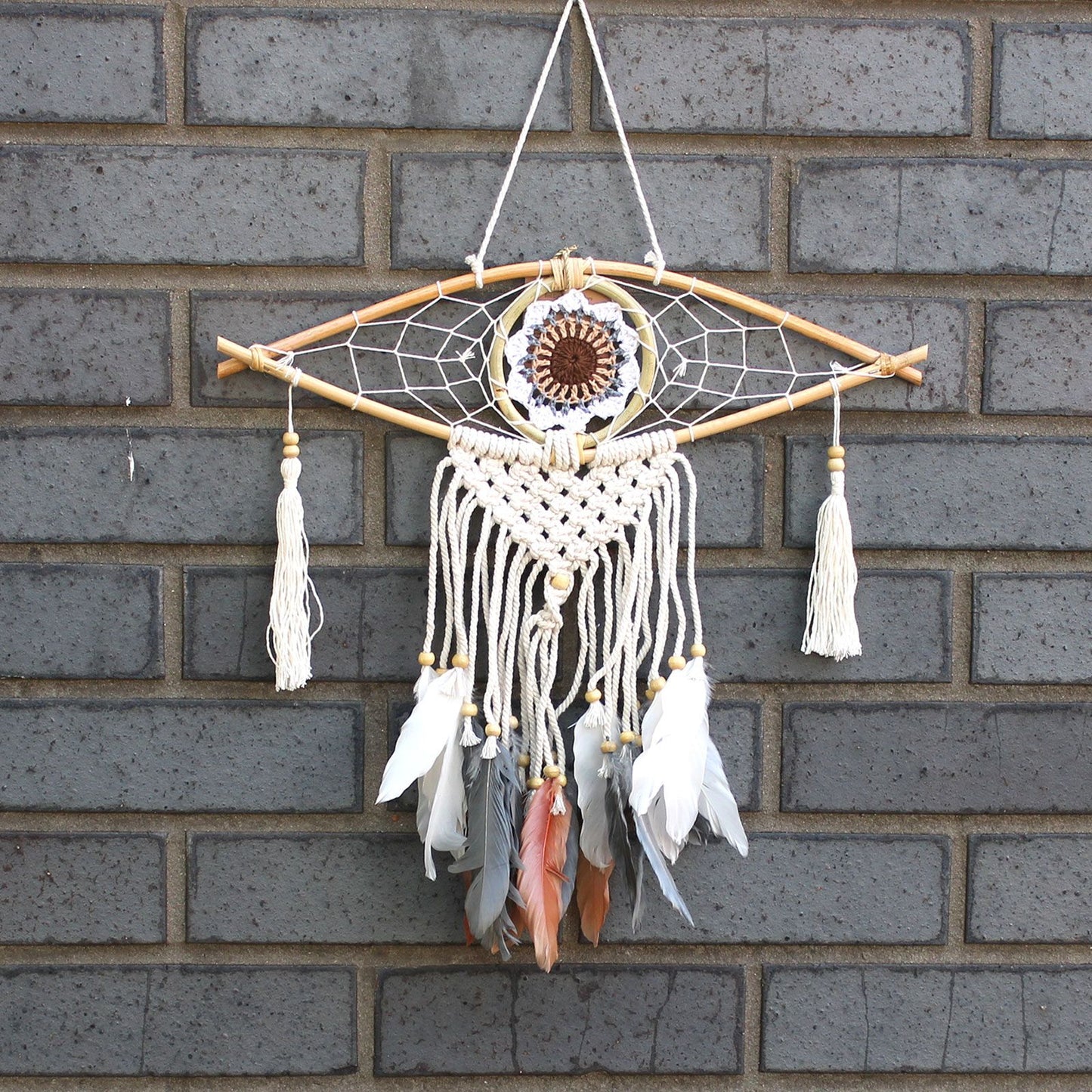 Small macrame dream catcher featuring a blue and white evil eye symbol at the centre of the woven web.