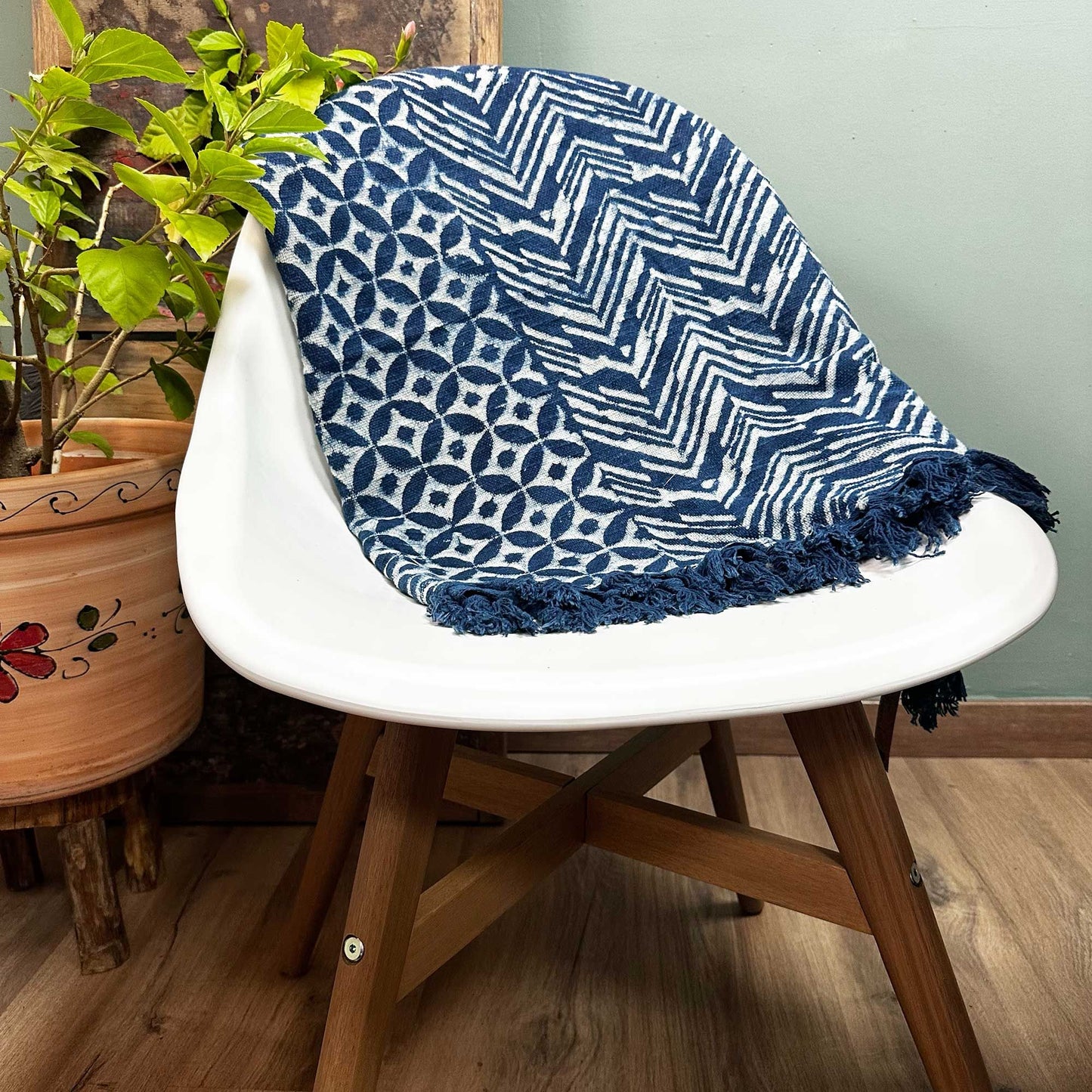 Close-up of a handmade indigo blue cotton throw with an intricate white Namoona wave pattern and fringed edges.