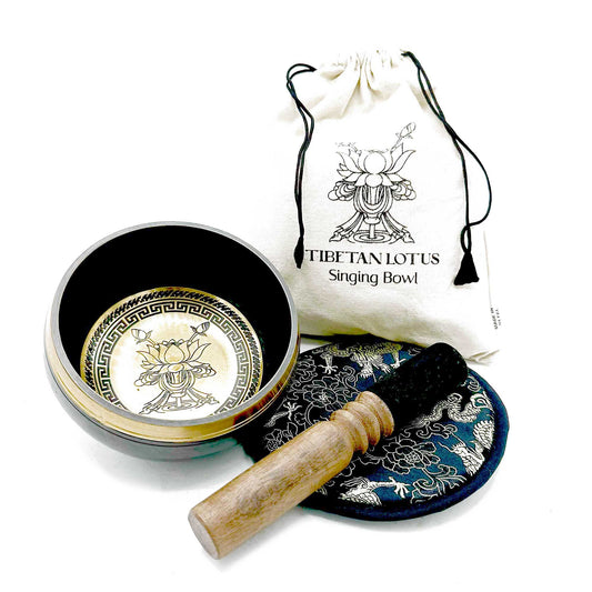 Hand-beaten 14cm metal singing bowl with an intricate engraved lotus flower design, wooden mallet, and patterned cushion.