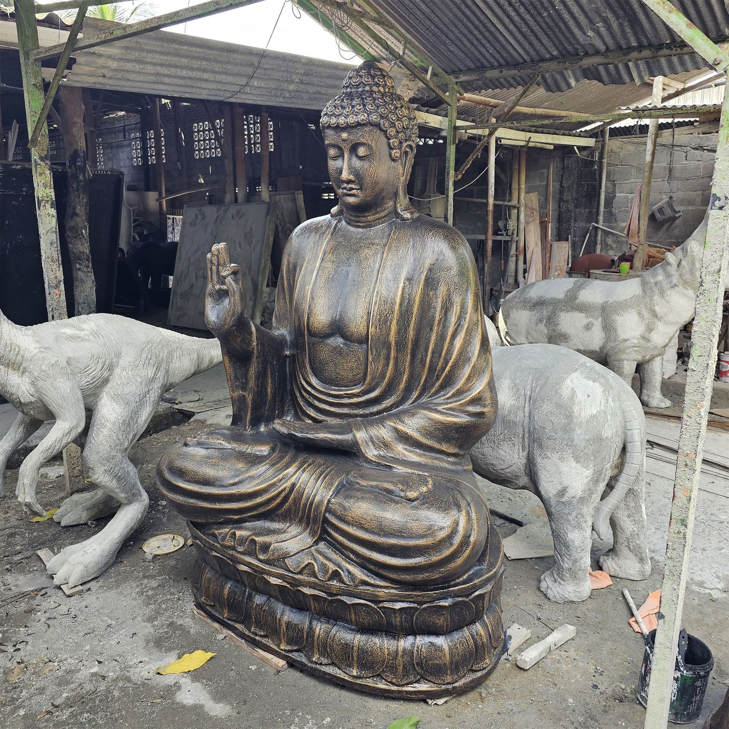 Large majestic Buddha statue in antique gold finish, seated in a teaching pose on a lotus flower base.