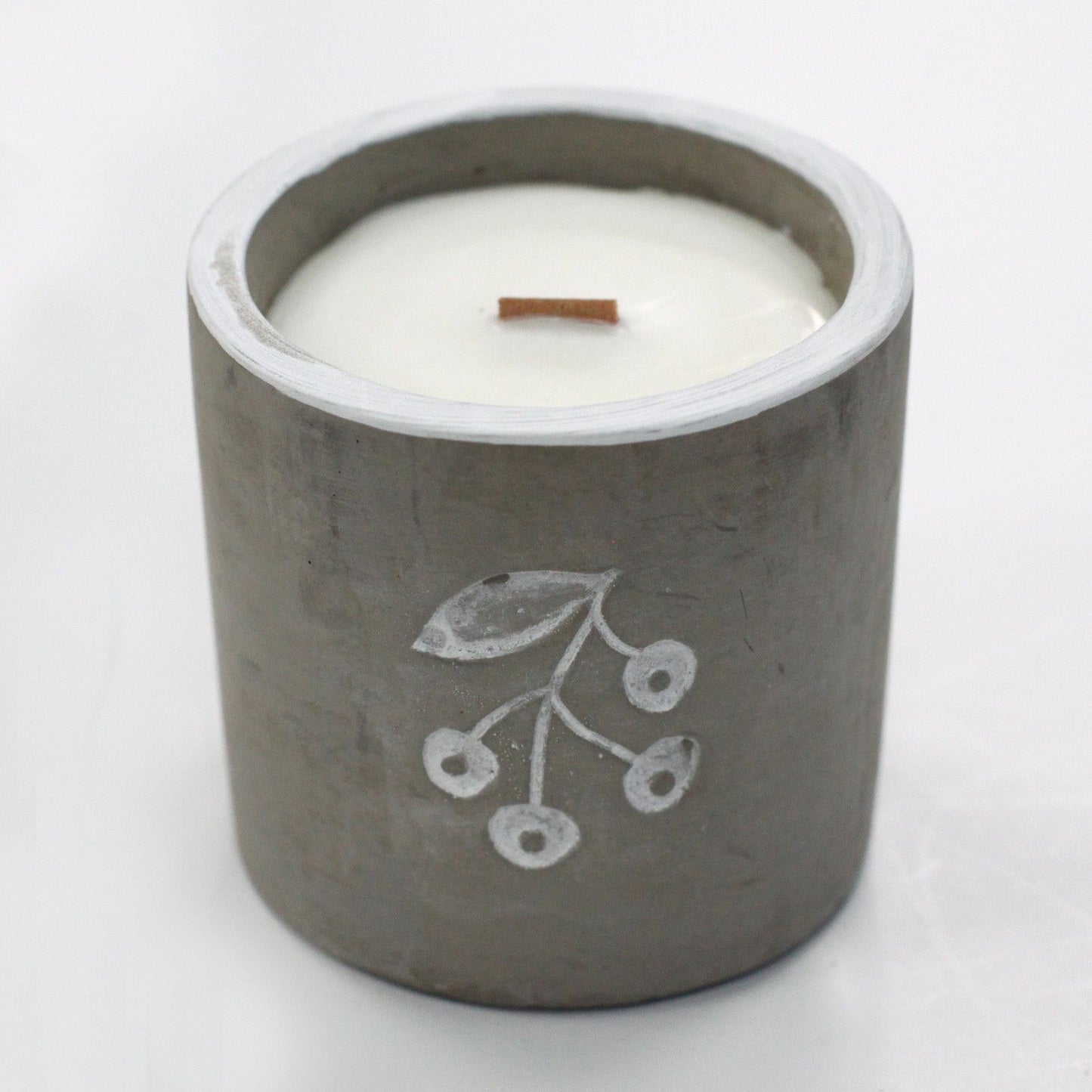 Handcrafted grey concrete candle pot with a natural wooden wick and smooth wax surface on a minimalist background.