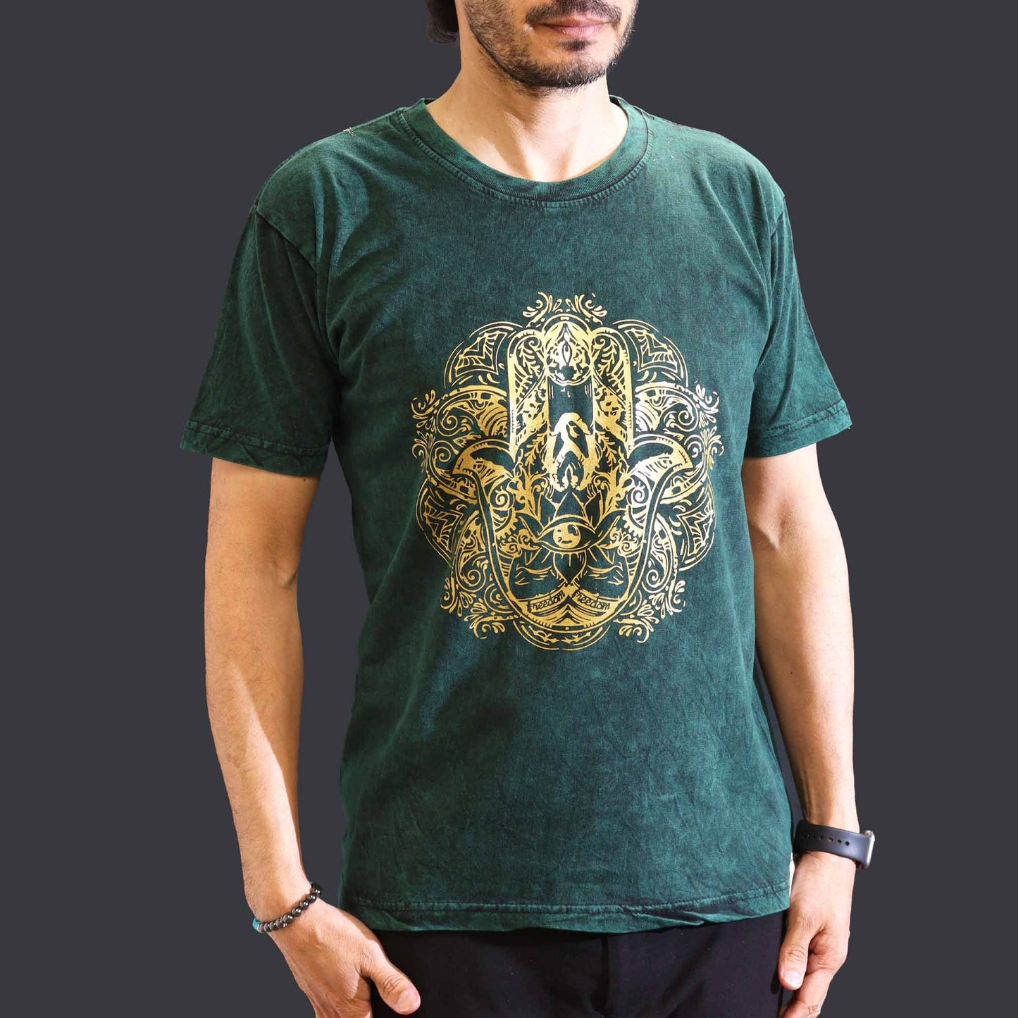 A green stone-washed t-shirt featuring a central Hamsa hand symbol in a relaxed nomadic style.