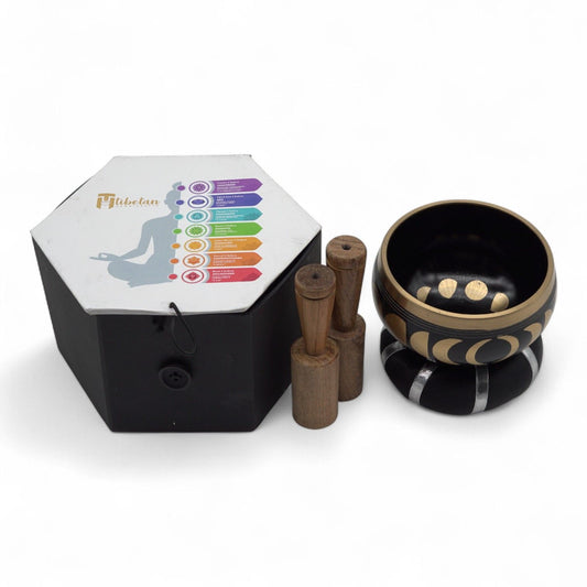Handcrafted black Tibetan singing bowl featuring engraved moon phase symbols, complete with a wooden striker and cushion.